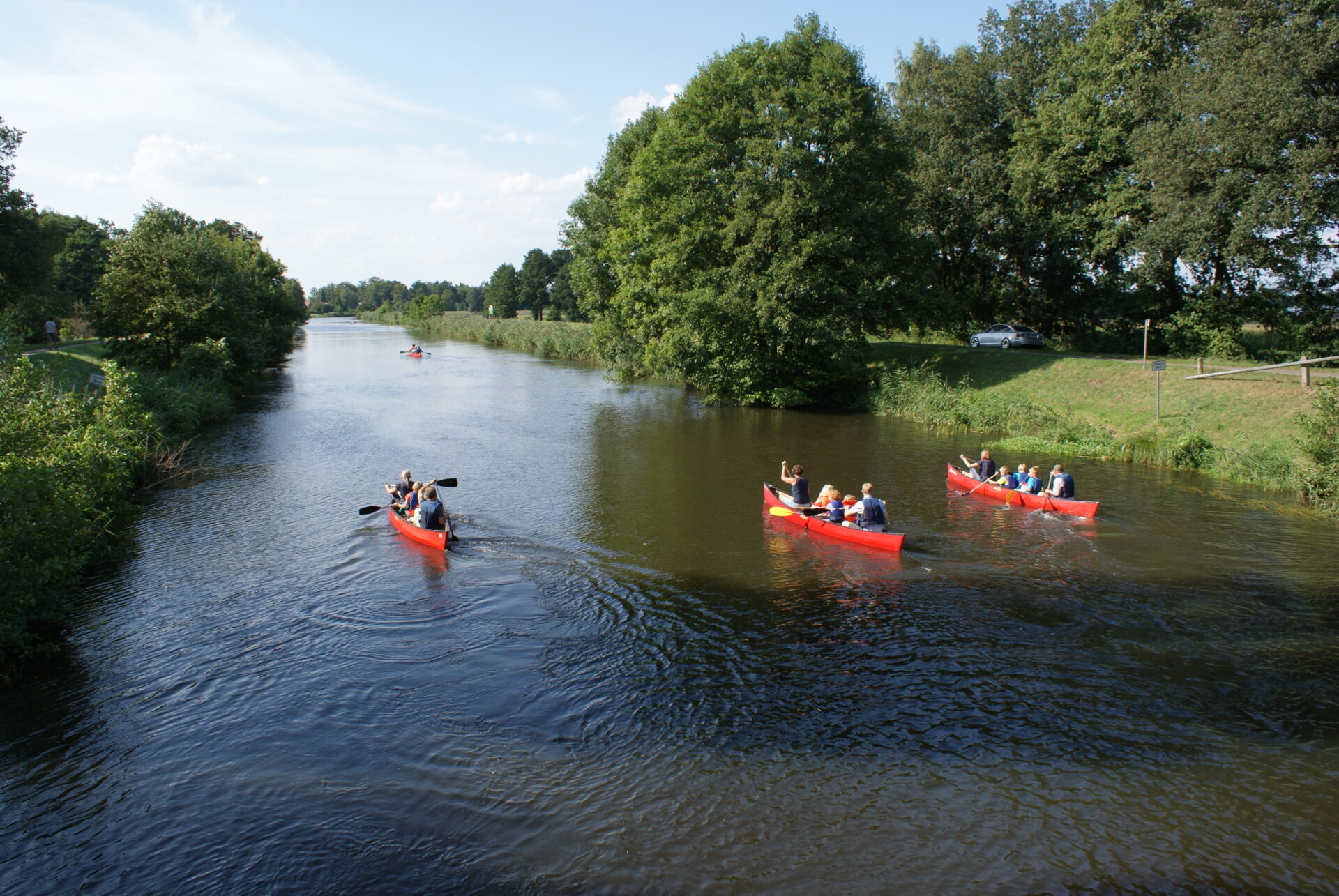 Drei Kanus mit jeweils 3 Personen paddeln nebeneinander auf der Hunte