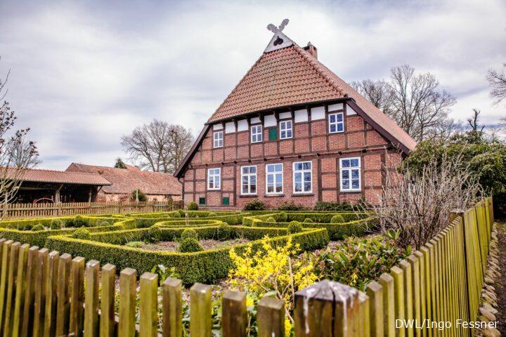 Gehannfors Hof – Prächtiges Fachwerkhaus mit gepflegtem Bauerngarten, umgeben von Holzzaun und Nebengebäuden.