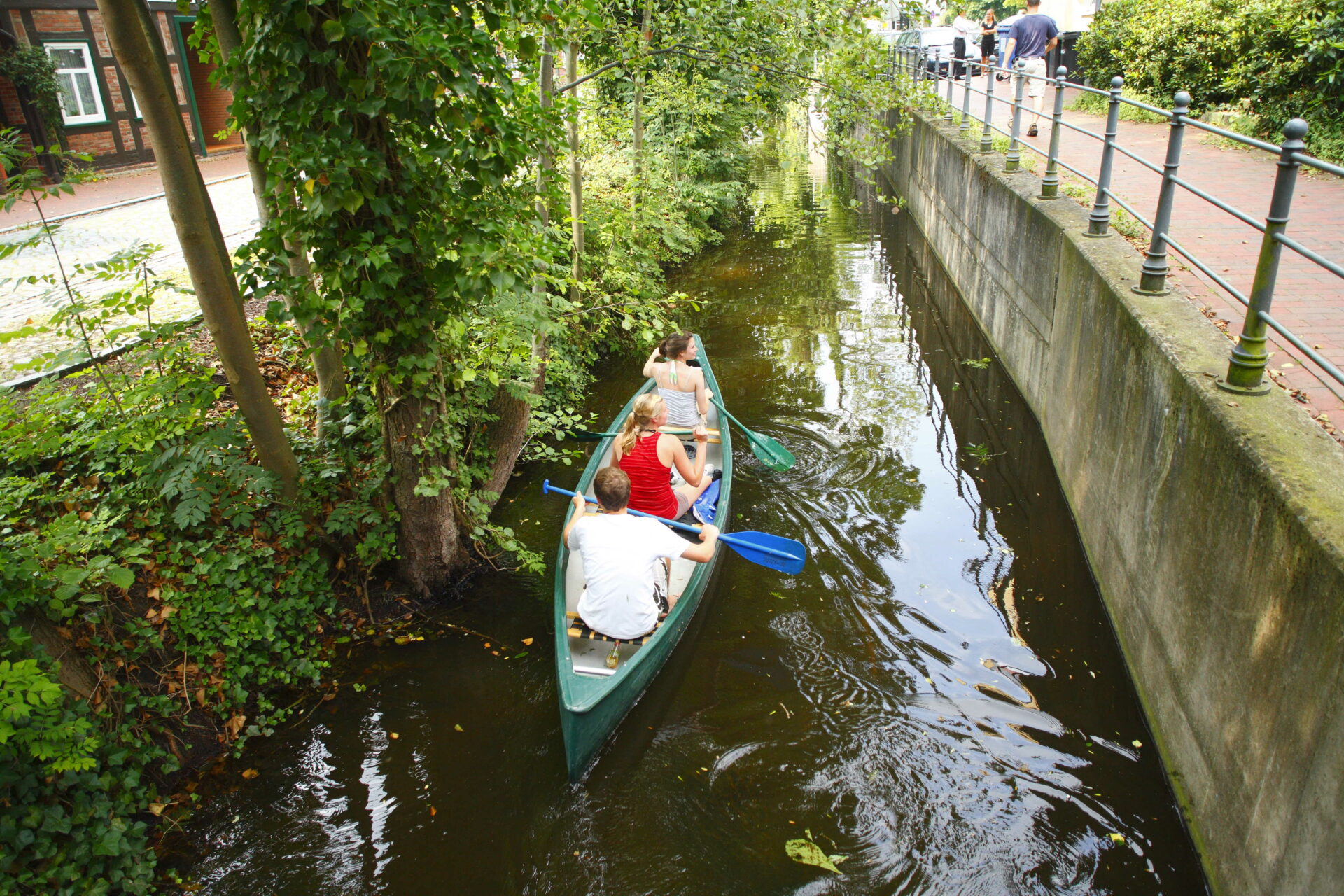 Drei junge Menschen in einem Kanu auf der Lohne neben einem Fußgängerüberweg