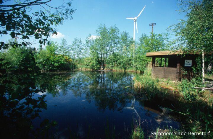 Teich im BUEZ mit Windrädern im Hintergrund