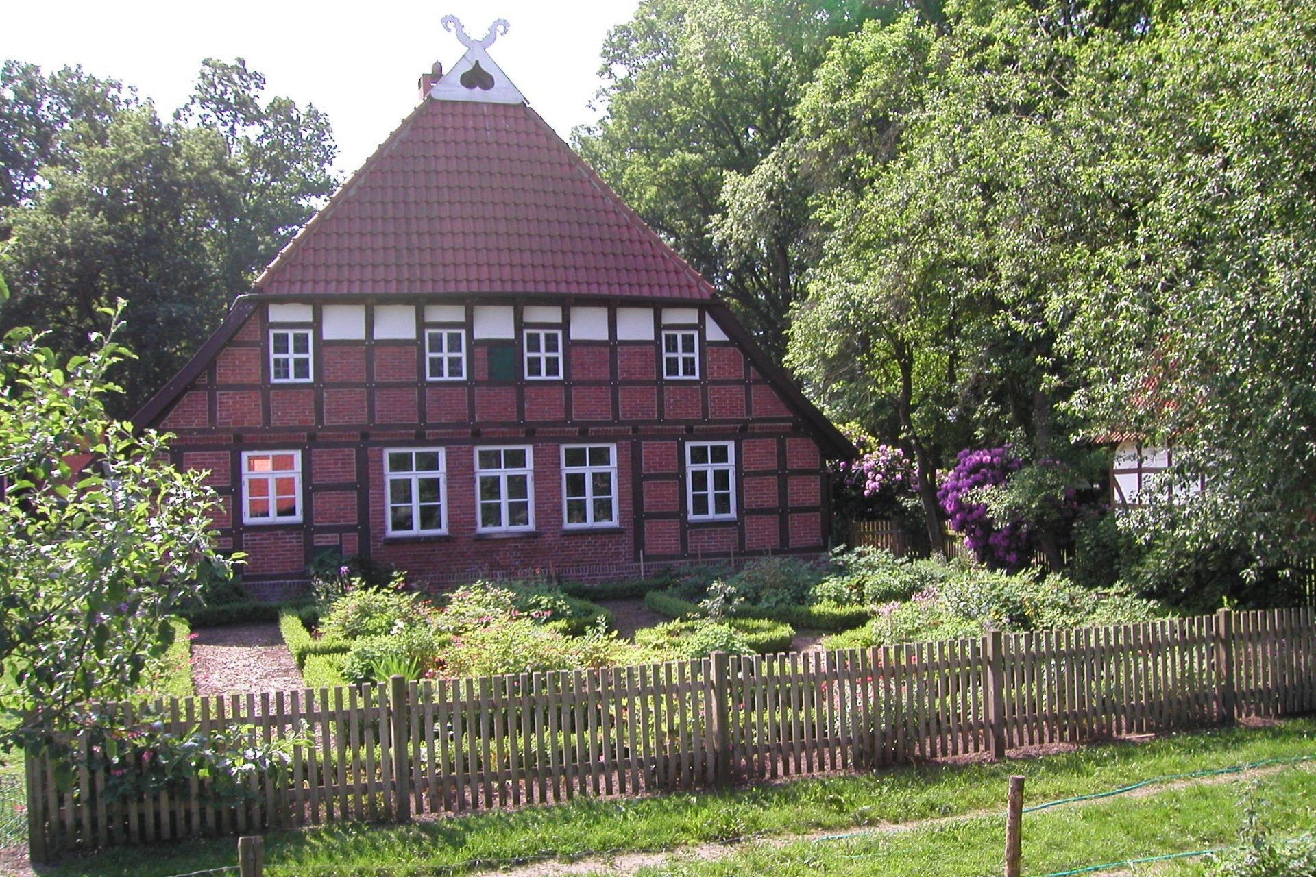 Ein altes rotes Fachwerkhaus mit Bauerngarten im Vordergrund.