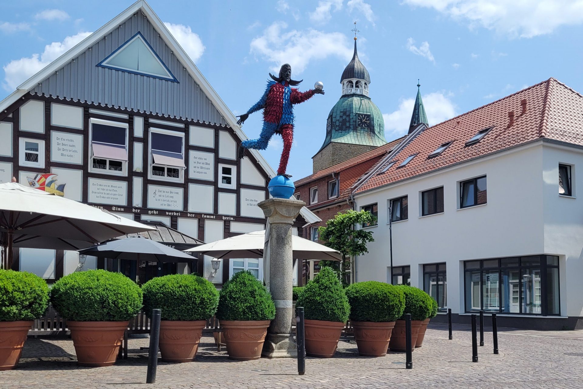 Die Statue Dammer Narr steht vor einem weißen Fachwerkhaus