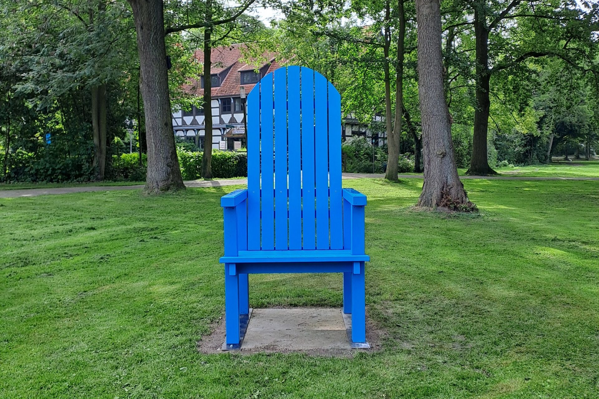 Stuhl Müntepark Ein blauer Stuhl steht auf einer Grasfläche im Müntepark, im Hintergrund sind Bäume.