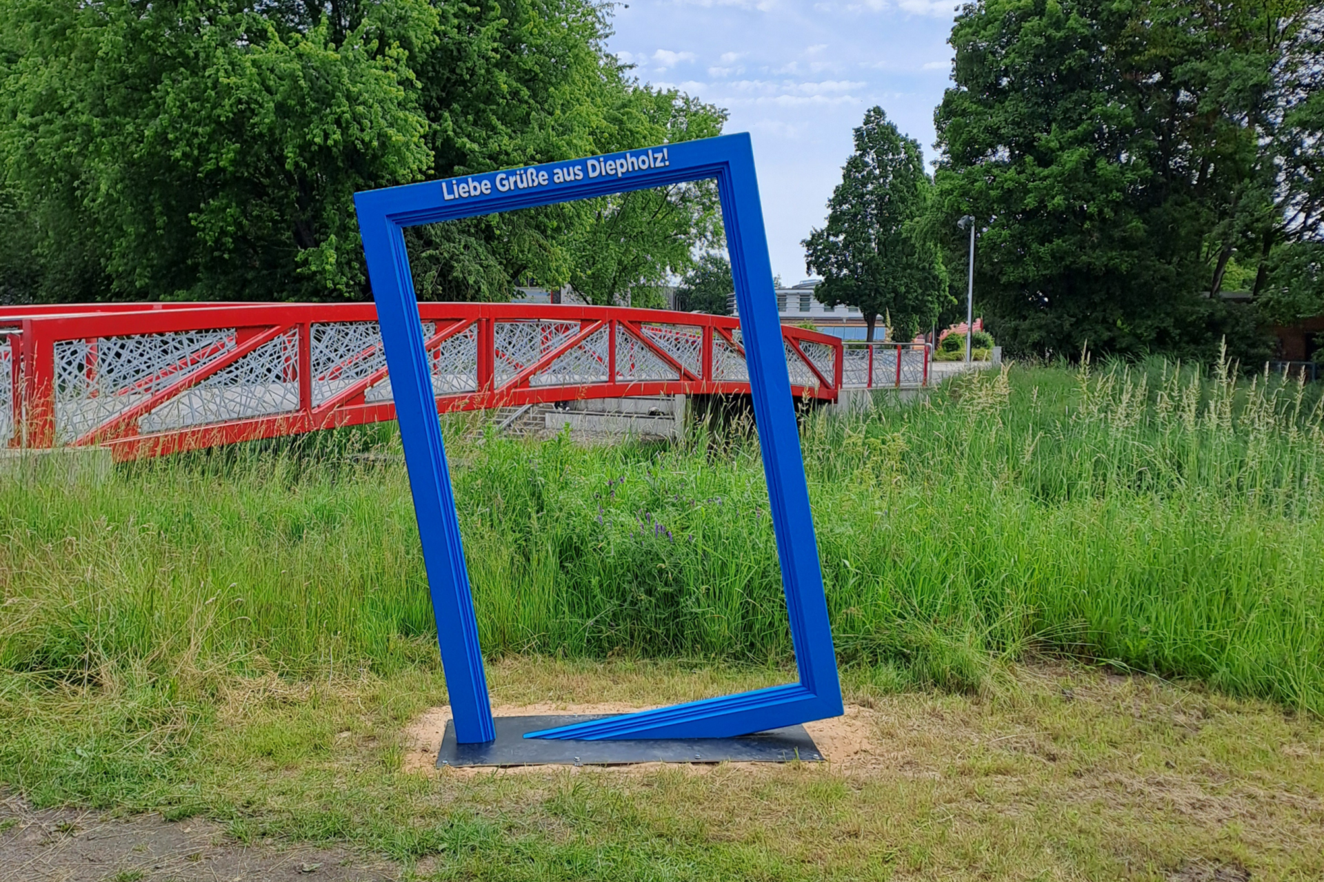 Thouarsbrücke_Diepholz Baluer Bilderrahmen auf Grasfläche vor der roten Thouarsbrücke