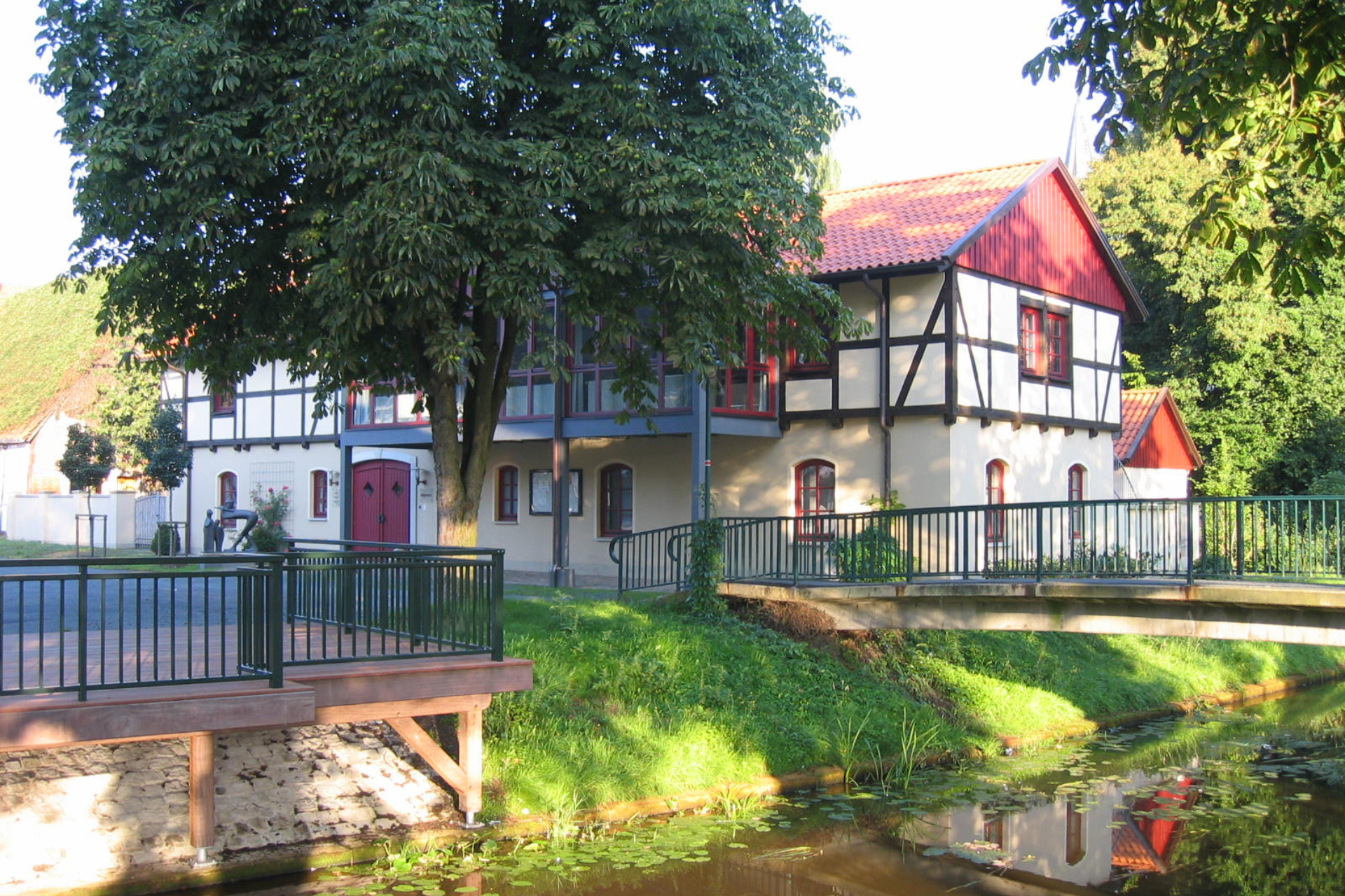 Fluss mit Brücke und Fachwerkhaus mit rotem Dach