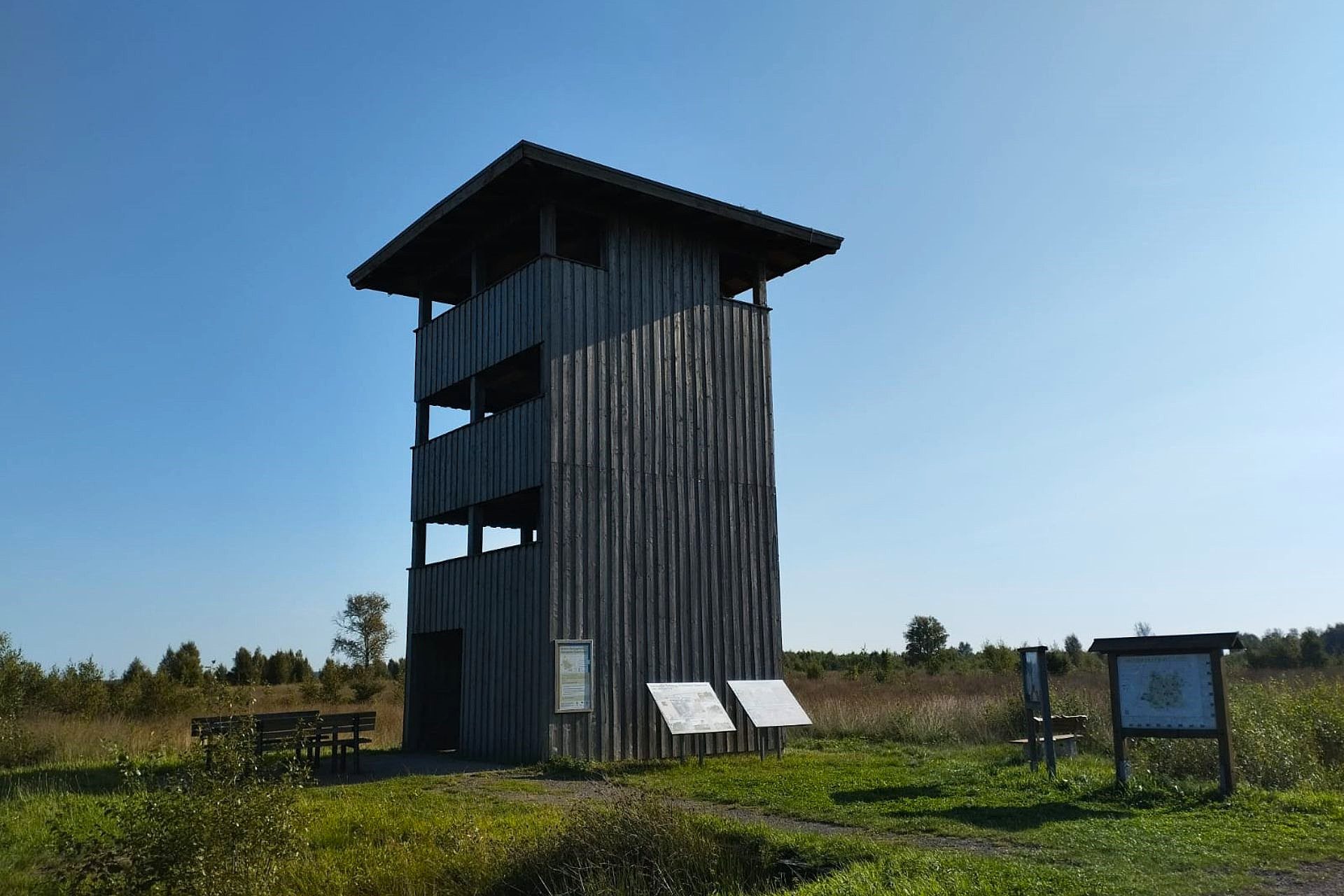 Aussichtsturm in Hemsloh mit verschiedenen Schautafeln im Vordergrund vor blauem Himmel